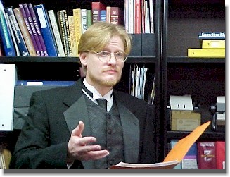 PHOTO: Tim Wheat speaking with a bookcase in the background